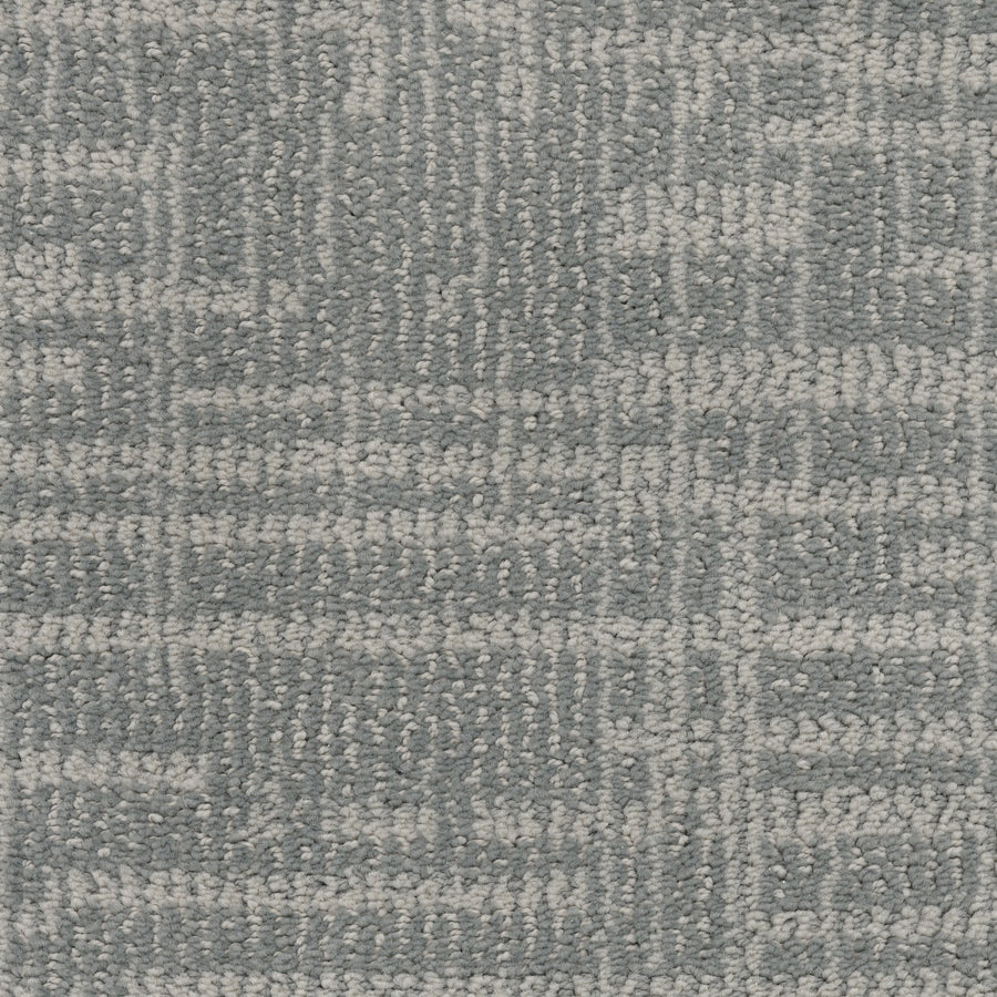 Close-up of Lineage Pet Friendly Carpet featuring a textured, geometric pattern in light gray and blue. Made with EnVisionSD yarn for lasting color, its intersecting lines and shapes bring a modern look to any space.