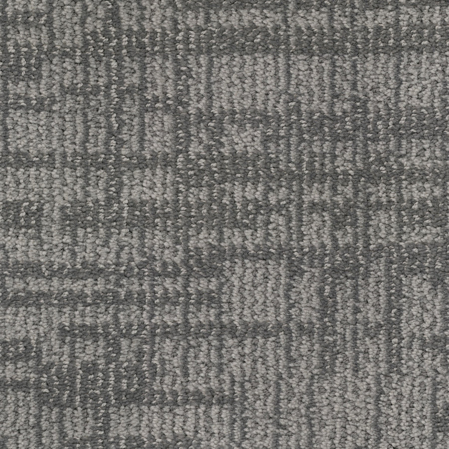Close-up view of Lineage Pet Friendly Carpet: a gray textured surface with a subtle, irregular grid-like pattern. Made from solution dyed EnVisionSD yarn, it offers a soft feel and modern, neutral tones—ideal for contemporary spaces.