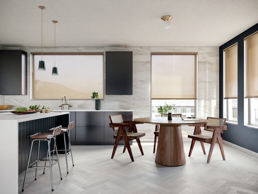 Modern kitchen and dining area with light herringbone flooring, a round wooden table, an island with barstools, minimalist black cabinets, pendant lights, and large windows featuring Modern Precious Metals® Aluminum Blinds for optimal light control.