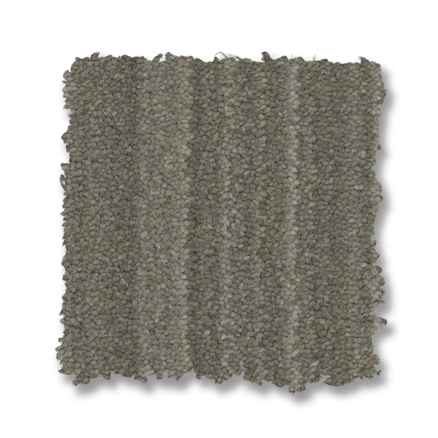 The Magnifique On Trend Carpet is shown as a square, textured gray swatch with subtle stripes on a white background. Its soft, dense fibers add timeless beauty and inviting texture to any space.