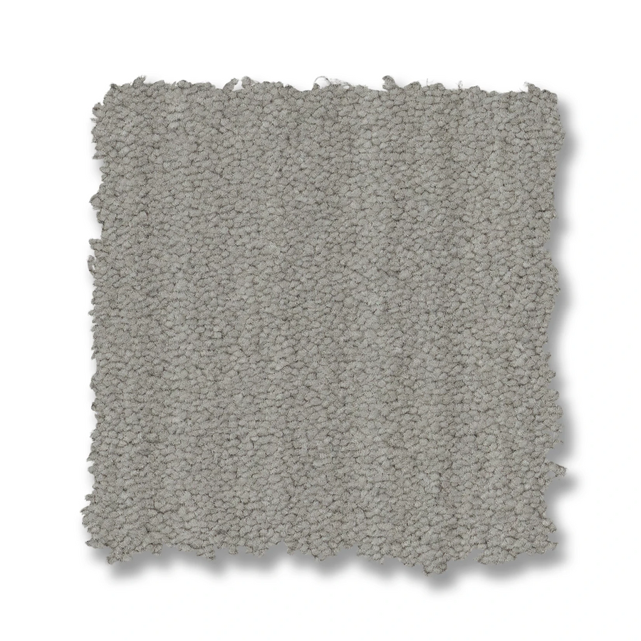 A square swatch of Magnifique On Trend Carpet in light gray with a textured finish and slightly uneven edges on a white background, offering timeless beauty and inviting texture to any space.