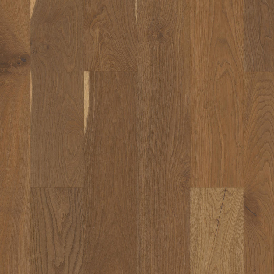 Close-up of Manchester 7 1/2" White Oak Hardwood flooring planks, featuring medium-brown tones, visible grain, and natural color variations, arranged in a classic staggered pattern for a timeless appearance.