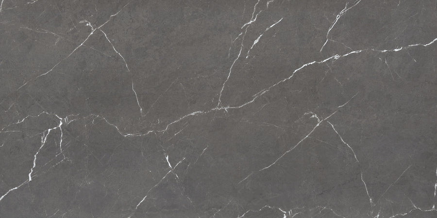 The Monaco 12x24 Porcelain Tile features a dark gray marble-look surface with white diagonal veining, offering a natural and textured appearance.