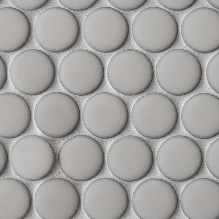 Close-up of New Form Penny Round Mosaic Tile—a modern tile with uniform, light gray matte circles and thin grout lines. Its geometric, grid-like pattern is ideal for contemporary backsplashes.