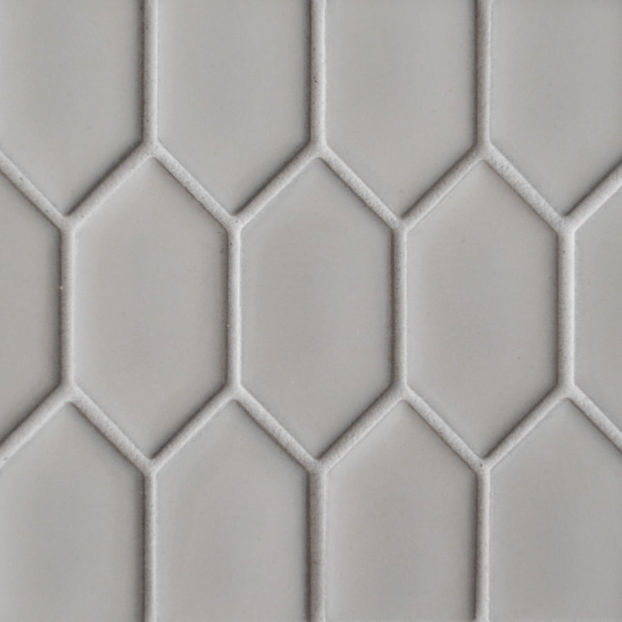 Close-up of a New Form Picket Mosaic Tile shower wall, showcasing a light gray geometric honeycomb pattern made from elongated hexagons outlined in a slightly darker shade.