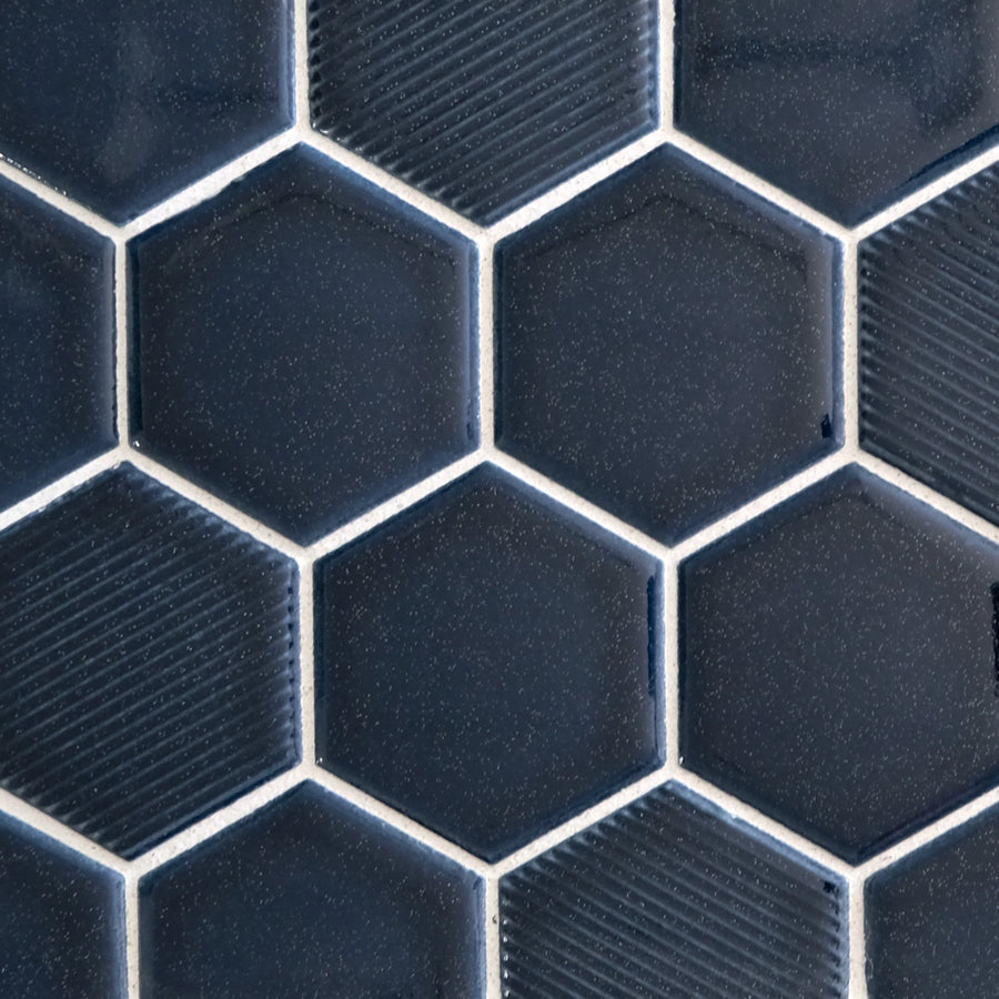 Close-up of New Form Hexagon Mosaic Tile in dark blue, featuring subtle texture variations and a honeycomb pattern with thin white grout—ideal for creating a striking backsplash or shower wall.