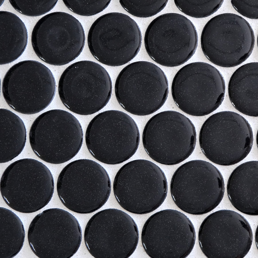 A close-up of New Form Penny Round Mosaic Tile shows glossy, round black tiles with white grout lines—ideal for creating a stylish backsplash or shower wall.