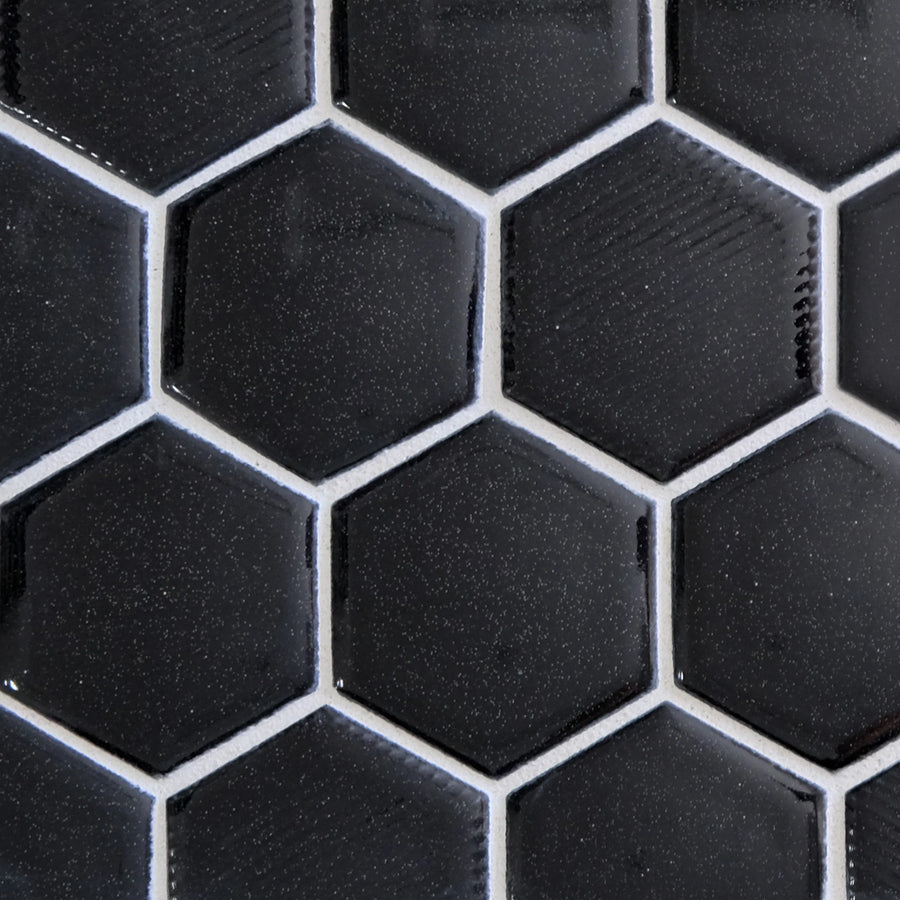 Close-up of New Form Hexagon Mosaic Tile in black, featuring glossy hexagonal pieces with white grout lines. The subtle texture and reflective finish create a striking honeycomb pattern, perfect for shower walls or kitchen backsplashes.