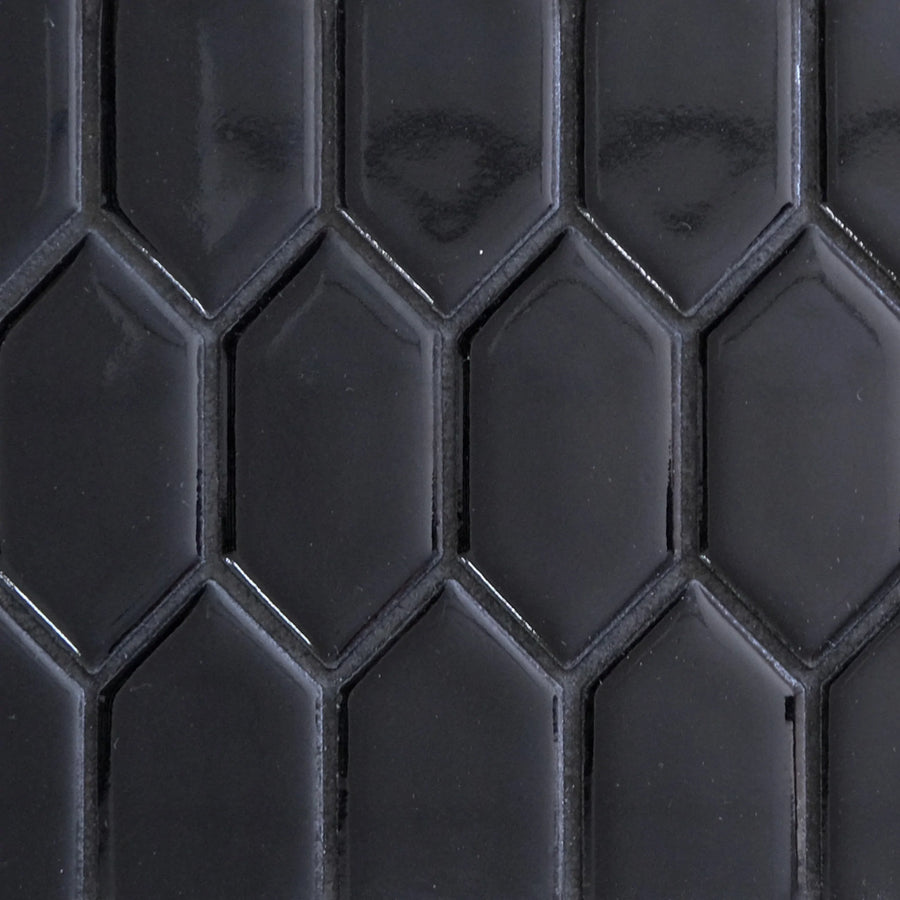 The New Form Picket Mosaic Tile features glossy black hexagonal tiles in a repeating pattern with visible grout lines, offering a smooth, reflective surface ideal for bold shower walls or modern backsplashes.