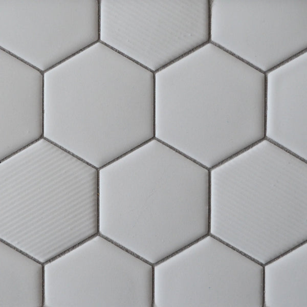Close-up of New Form Hexagon Mosaic Tile: white hexagonal tiles in a honeycomb pattern with subtle texture variations and visible grout—ideal for adding style to shower walls or backsplashes.