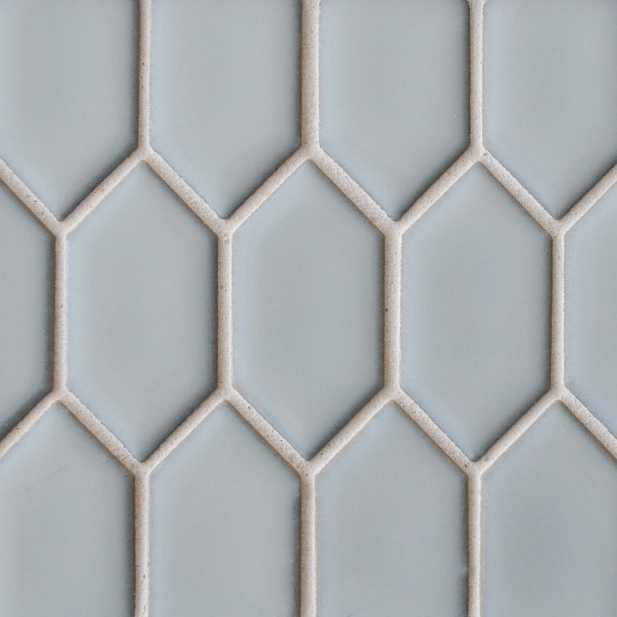 The New Form Picket Mosaic Tile features a light gray geometric design of elongated hexagons with white grout, creating a chic honeycomb look—ideal for modern shower walls or backsplashes.