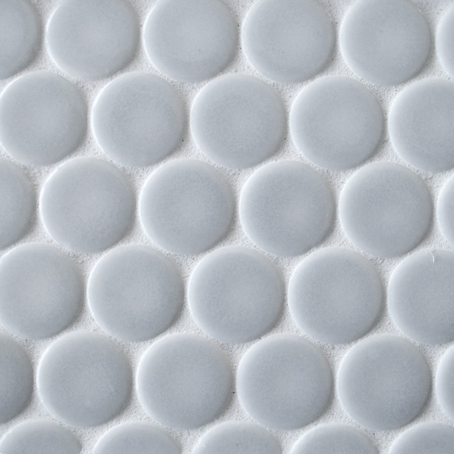 Close-up of New Form Penny Round Mosaic Tile featuring a repeating pattern of raised, white circular tiles—ideal for adding a stylish touch to any backsplash or shower wall.