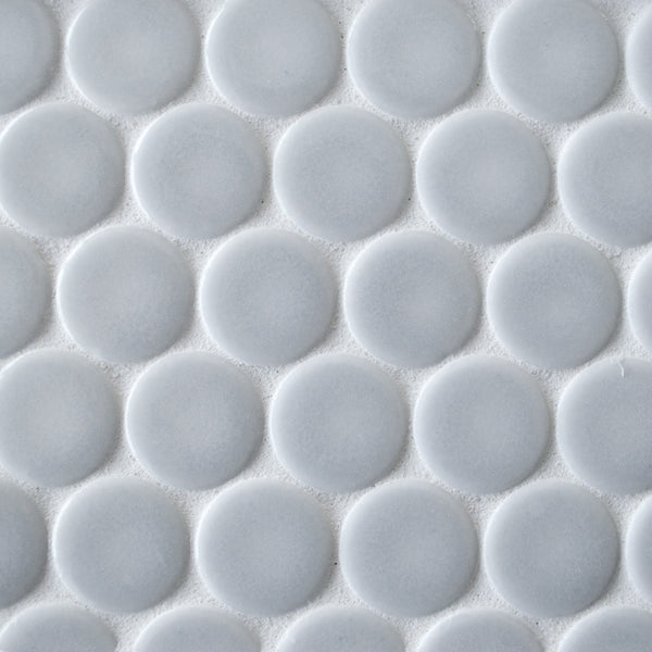 Close-up of New Form Penny Round Mosaic Tile featuring a repeating pattern of raised, white circular tiles—ideal for adding a stylish touch to any backsplash or shower wall.