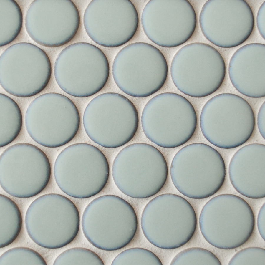 A close-up of New Form Penny Round Mosaic Tile in light blue, featuring round tiles arranged in a grid with white grout—ideal for a stylish shower wall or backsplash.