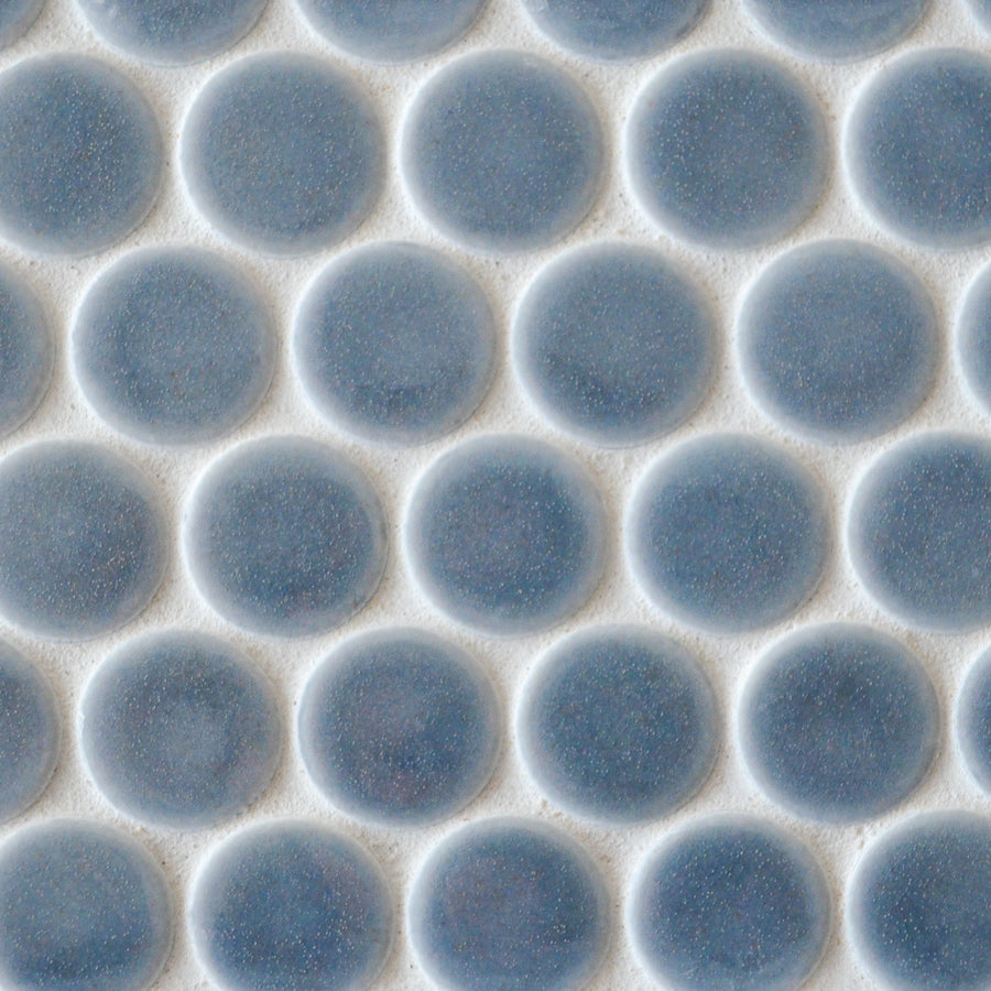 Close-up of New Form Penny Round Mosaic Tile: white surface with evenly spaced, round, blue-gray tiles in a grid pattern—perfect for a modern shower wall or backsplash.