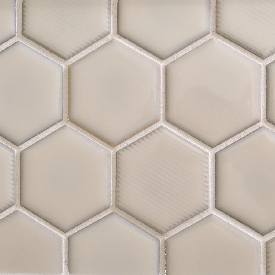 A close-up of New Form Hexagon Mosaic Tile in beige, featuring glossy hexagonal pieces in a honeycomb pattern with thin white grout—ideal for adding style to shower walls or backsplashes.