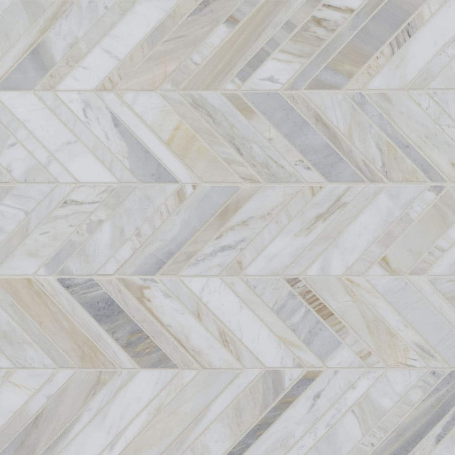 Olympia Sandalwood Chevron Marble Mosaic features polished marble tiles in white, cream, beige, and light gray arranged diagonally in a V-shaped chevron pattern with subtle veining for an elegant, timeless look.