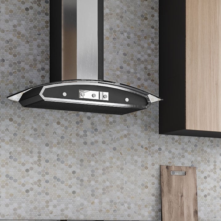 A modern stainless steel and glass range hood is mounted on a wall with Olympia Sandalwood Penny Round Marble Mosaic tile. A portion of a wooden cabinet and a cutting board appear on the right side.