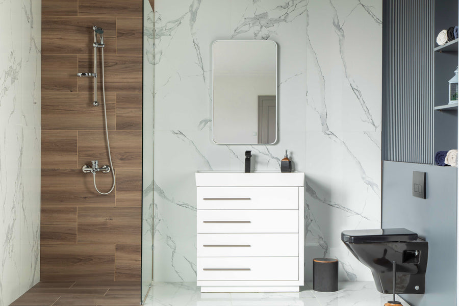 Modern bathroom featuring an Adora 32" Vanity with sleek porcelain top, wood-paneled shower, black toilet, and shelves of neatly stacked towels set against marble-patterned walls and floor.