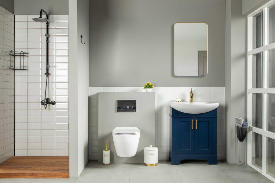 Modern bathroom with a walk-in shower, wall-mounted toilet, and the Luna 24" Vanity on the right featuring a blue cabinet and gold faucet. A mirror above the sink completes the minimalist, neutral décor with free-standing style.
