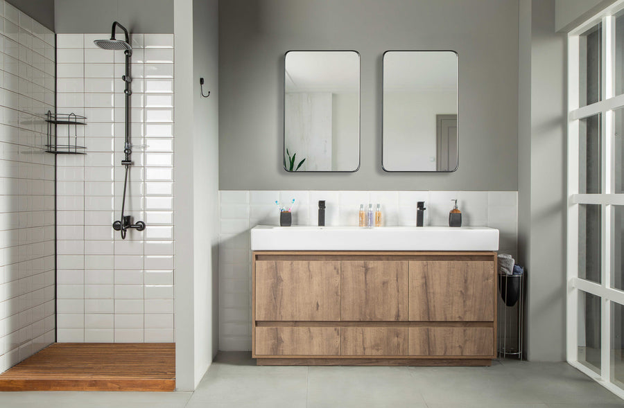 Modern bathroom with a walk-in shower and wooden floor, anchored by the Romina 60" Vanity—an elegant oak double-sink vanity with wood cabinets, two mirrors above, and toiletries on the counter.