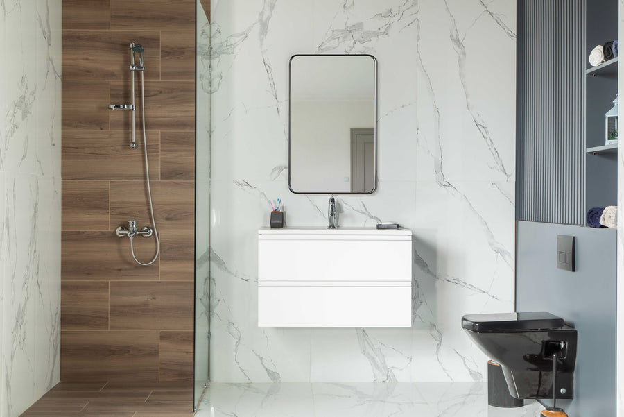 Modern bathroom with white marble walls, a Simena 30" floating vanity with soft-close drawers and mirror, black toilet, towel shelves, and a shower area with wood-textured tiles and a handheld showerhead.