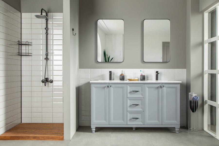 Modern bathroom with a walk-in shower on the left, white subway tiles, and wood floor. On the right, an Isabel 60" Vanity features double sinks, two mirrors above, and various toiletries on the counter.