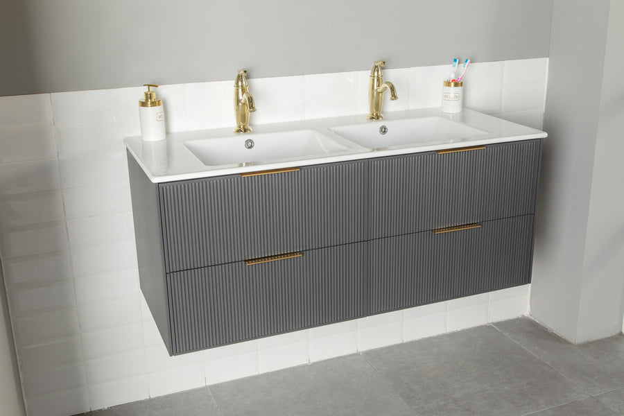 The Sorrento 48" Vanity features two sinks with gold faucets, a gray ribbed cabinet, white tiled backsplash, soap dispenser, and cup for toothbrushes, all set on a gray tiled floor.