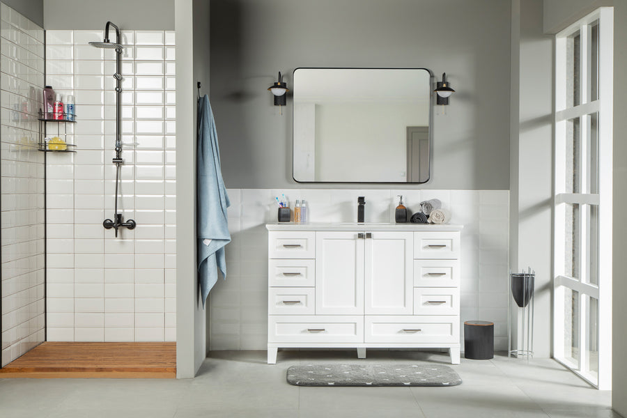 Modern bathroom with the Paloma 42" Vanity, soft close drawers, large mirror, two wall lights, walk-in shower with white tiles, wood floor, and blue towel on a hook. Tall right-side windows let in abundant natural light.