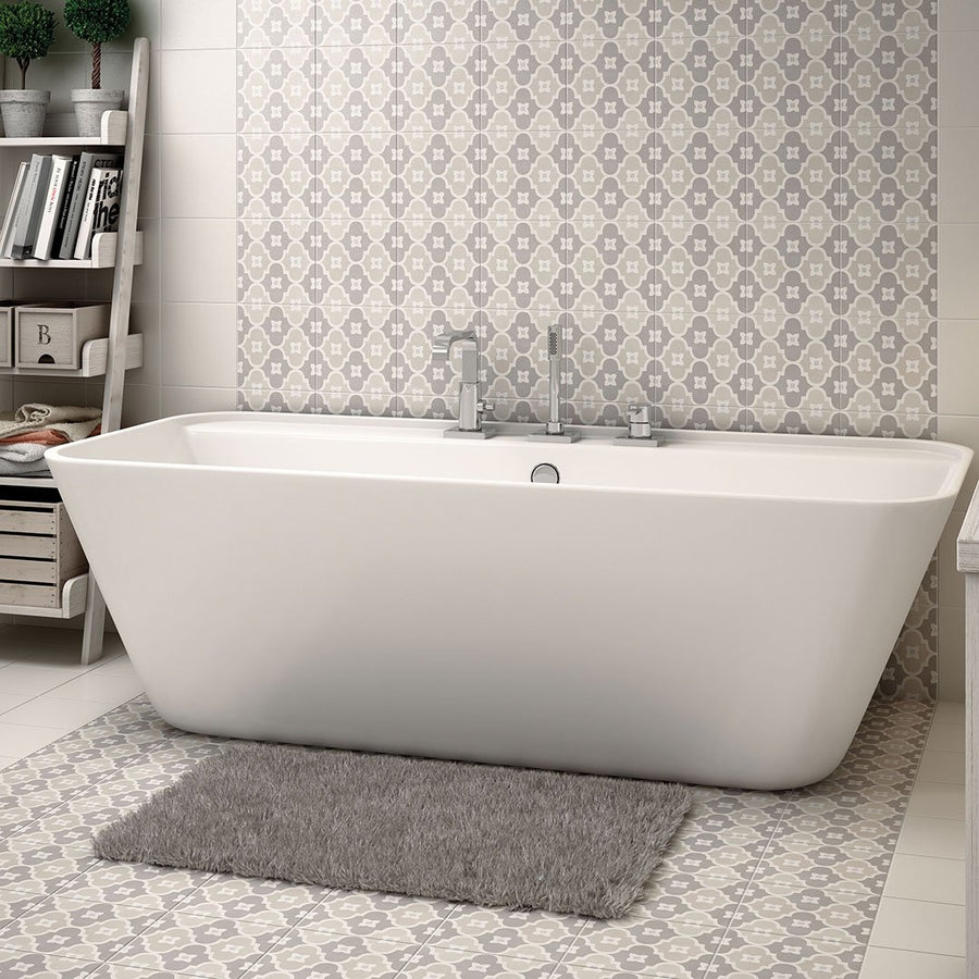 A modern white bathtub with a gray rug in front sits against a Caprice Pastel Bowtie Patterned Tile wall, while shelves with towels and baskets add to the bathroom’s clean, cozy style.