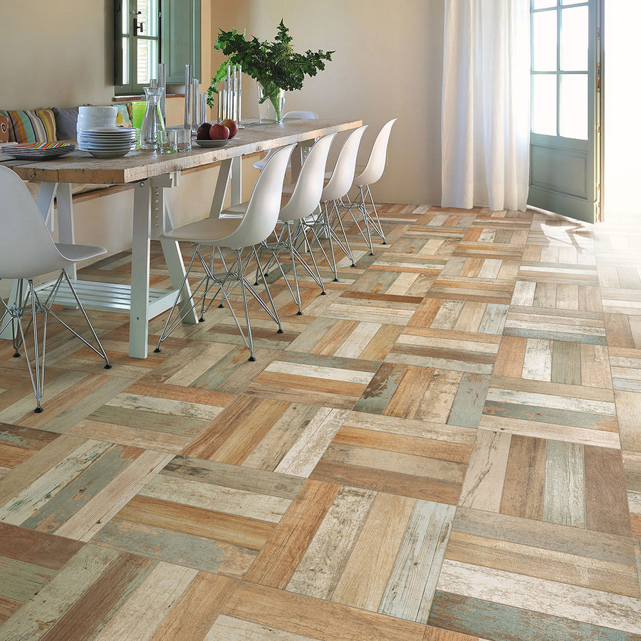 A dining room features a rustic wooden table, six white chairs, and Kings Bretagne 17 3/4 x 17 3/4 Patterned Tile flooring. Sunlight through glass doors with white curtains highlights the vintage industrial design.