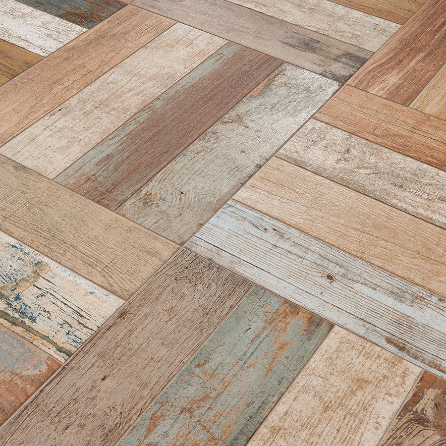 A close-up of Kings Bretagne 17 3/4 x 17 3/4 patterned tile, showcasing a rustic wood grain look in brown, beige, blue, and white arranged diagonally—ideal for vintage industrial spaces.