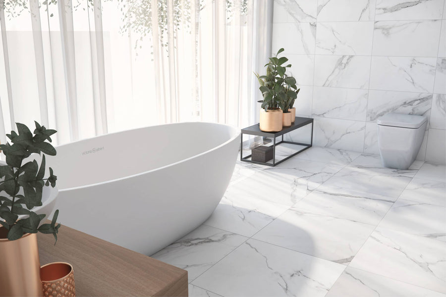 Modern bathroom featuring Buckingham Palace 12x24 Porcelain Tile flooring, a white freestanding tub, square toilet, wooden cabinet, potted green plants, and sheer curtains allowing in natural light.