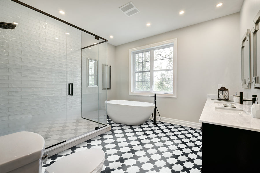 Modern bathroom featuring a large glass shower, freestanding oval bathtub by the window, dual sinks with mirrors, and a stunning Casablanca Marble & Stone Mosaic floor. Bright, minimal design with neutral walls and recessed lighting.