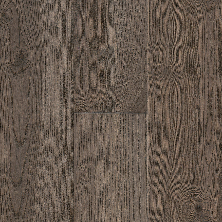 Close-up of Urban Forest 6.5" Ash Hardwood flooring showcases dark brown boards with natural grain, visible knots, a matte finish, and impressive scratch resistance for a refined rustic look.
