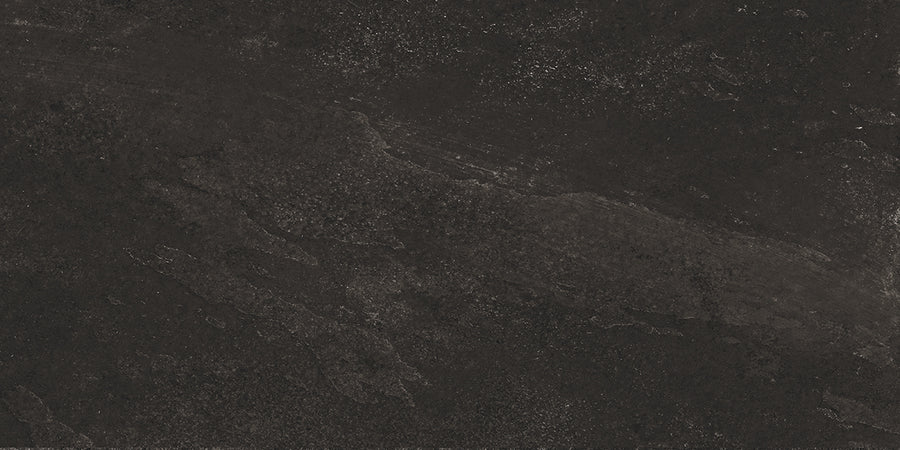 Shyft 12x24 Rectified Porcelain Tile features a dark, textured surface with subtle gray and black variations, rough patches, and natural mineral patterns—capturing the elegant look of Brazilian slate in durable porcelain.