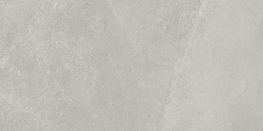 A close-up of Shyft 12x24 Rectified Porcelain Tile shows a light gray, Brazilian slate-inspired textured surface with subtle variations and diagonal patterns.