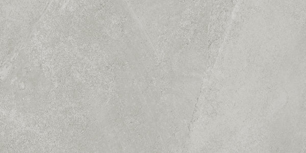 A close-up of Shyft 12x24 Rectified Porcelain Tile shows a light gray, Brazilian slate-inspired textured surface with subtle variations and diagonal patterns.