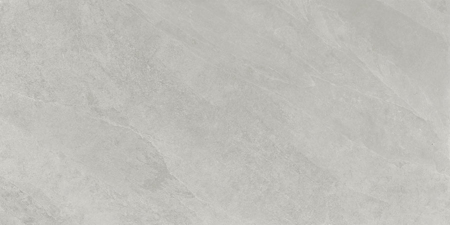 Shyft 24x48 Rectified Porcelain Tile features a light gray, marble-inspired surface with subtle veins and textured patterns. Its smooth, matte finish and varied gray shades offer the elegant look of natural Brazilian slate.