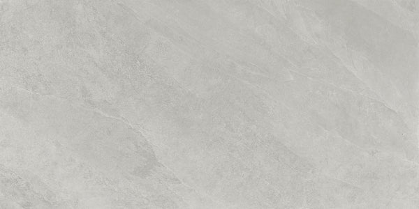 Shyft 24x48 Rectified Porcelain Tile features a light gray, marble-inspired surface with subtle veins and textured patterns. Its smooth, matte finish and varied gray shades offer the elegant look of natural Brazilian slate.