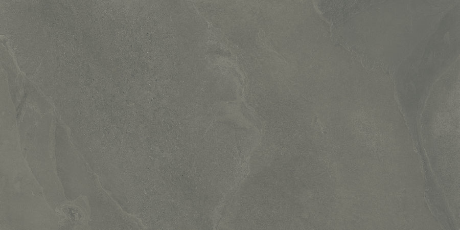A close-up of the Shyft 24x48 Rectified Porcelain Tile reveals a textured, dark gray slate look with natural streaks, organic patterns, and subtle color variations that showcase its realistic and rugged details.