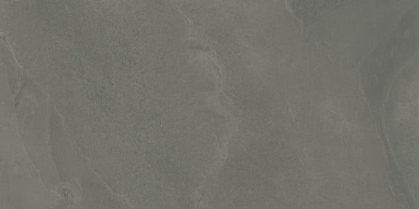 A close-up of the Shyft 24x48 Rectified Porcelain Tile reveals a textured, dark gray slate look with natural streaks, organic patterns, and subtle color variations that showcase its realistic and rugged details.