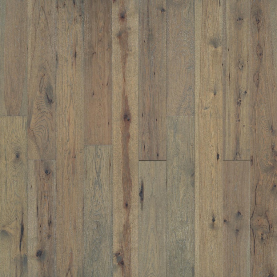 A close-up of Westport 7 1/2" Hardwood reveals wide planks of French White Oak, highlighting natural grain, knots, and rustic charm with varied brown and tan shades.