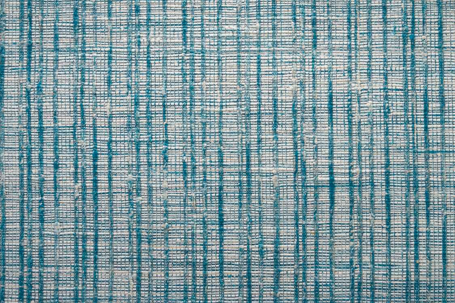 The Texture Weave On Trend Carpet is a hand-woven flatweave rug with vertical and horizontal teal blue lines on a light gray background, forming an abstract, grid-like pattern.
