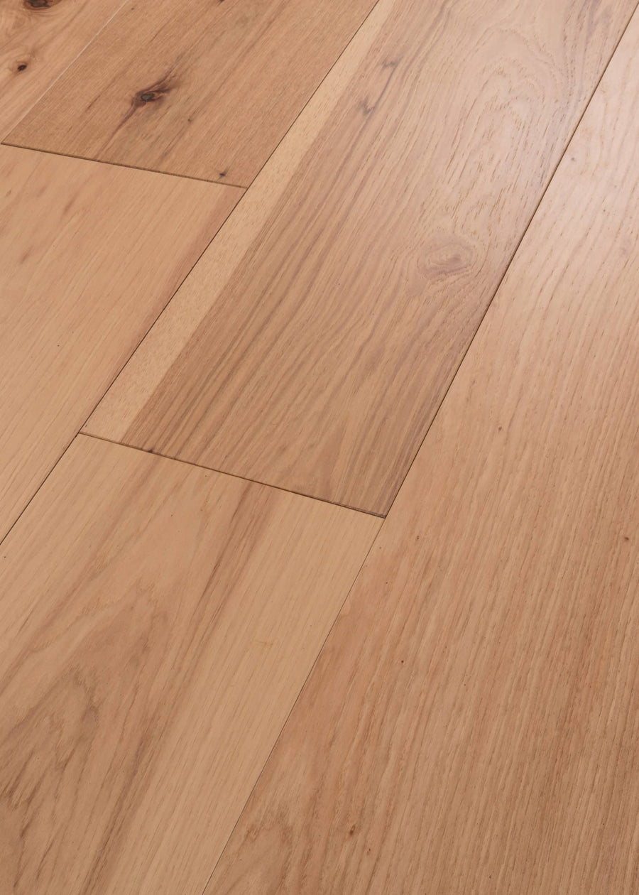 Close-up of Vogue 9 1/4" Hickory & Red Oak Hardwood flooring, showcasing light brown tones, natural grain patterns, and subtle knots in a seamless horizontal layout.
