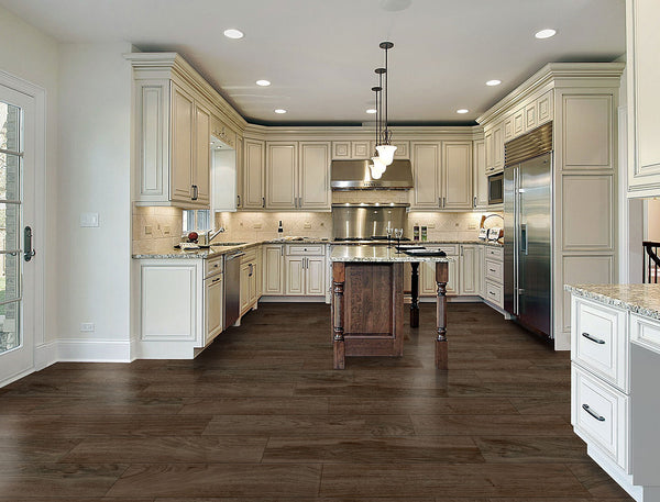 Spacious, modern kitchen with white cabinets, stainless steel appliances, a central wooden island, granite countertops, pendant lighting, a glass door to the outside, and Riverwood 6x36 Wood Plank Tile flooring.