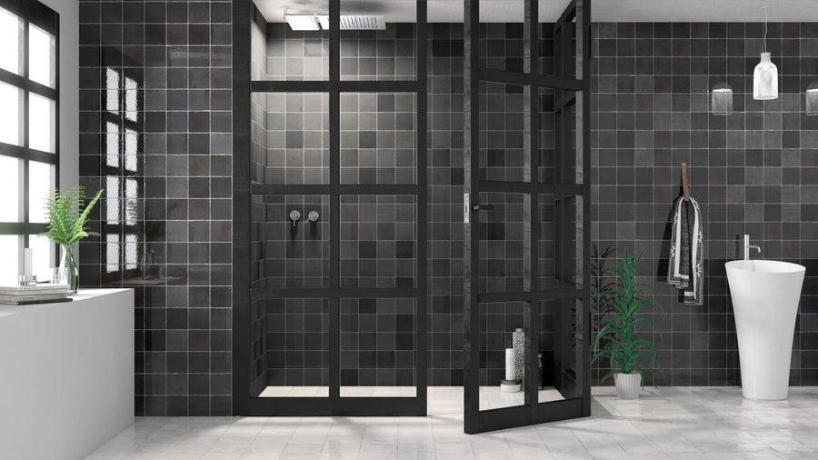 Modern bathroom with black tiled walls, glass shower enclosure with black frames, white pedestal sink, towel rack, and potted plants. Large windows provide natural light, while Zellige 5x5 Glossy Subway Tile flooring adds artisanal charm.