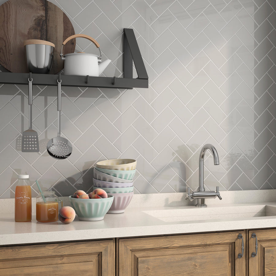 Modern kitchen countertop with wooden cabinets, pastel mixing bowls, fresh peaches, jars of peach tea, and utensils hanging above, set against a light U761 3x6 Glossy Subway Tile backsplash.