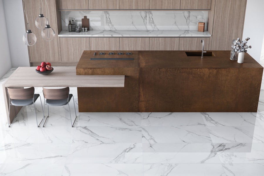 Modern kitchen featuring a rust-colored island with cooktop and sink, light wood dining table for two, and Buckingham Palace 24x48 Porcelain Tile in a marble look on the floor and backsplash, plus open shelves and pendant lights.