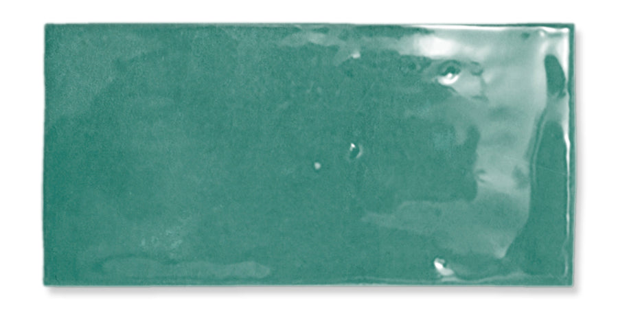 The Fez 2.5x5 Subway Tile is a rectangular, glossy teal glazed ceramic tile featuring a smooth, slightly uneven surface and rounded edges.
